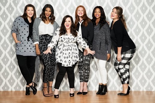 Melissa McCarthy poses with models in her HSN line. It's all grey, black and white.